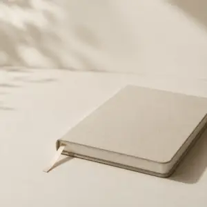 Closed neutral-toned notebook in soft natural light representing reflection, clarity, and personal transformation
