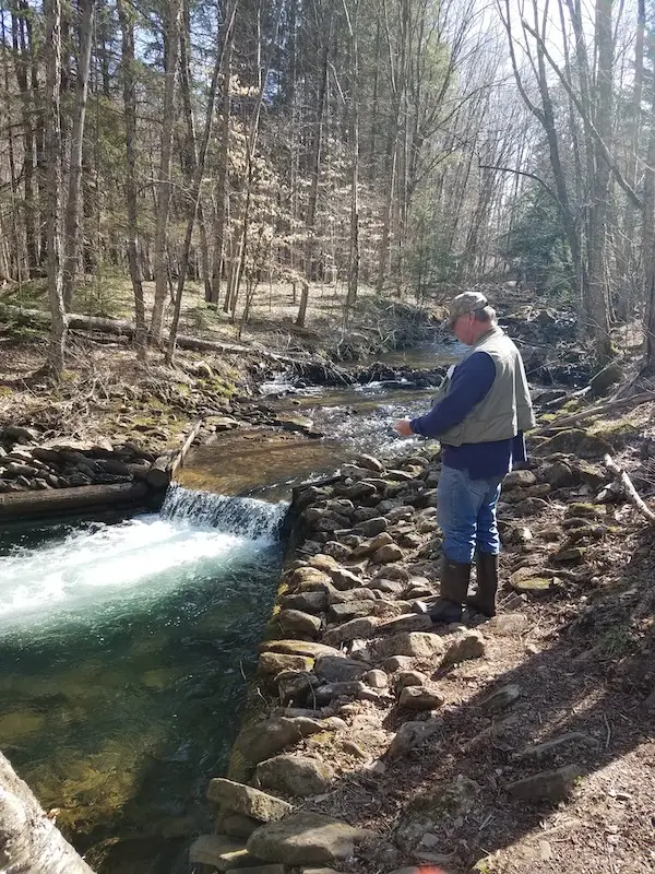 Man fishing in a mountain stream beside a small waterfall during a life reset retreat focused on reflection, clarity, and personal growth.